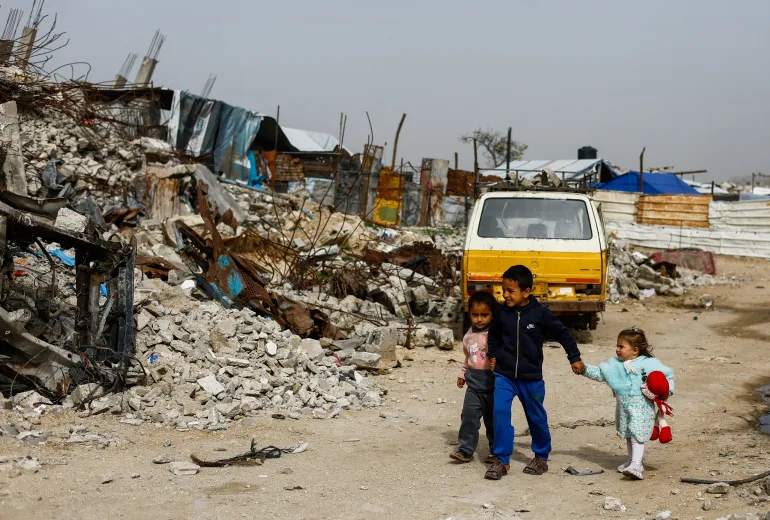 Palestinian children walk past the rubble of residential buildings destroyed during the war, in Gaza City, January 28, 2026. REUTERS/Mahmoud Issa TPX IMAGES OF THE DAY