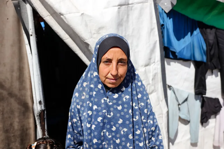 Amal Jouda, displaced from Beit Lahia in northern Gaza to Deir al-Balah two years ago, says all she asks for is a dignified life for herself and her children, no matter which party delivers it [Abdelhakim Abu Riash/Al Jazeera]