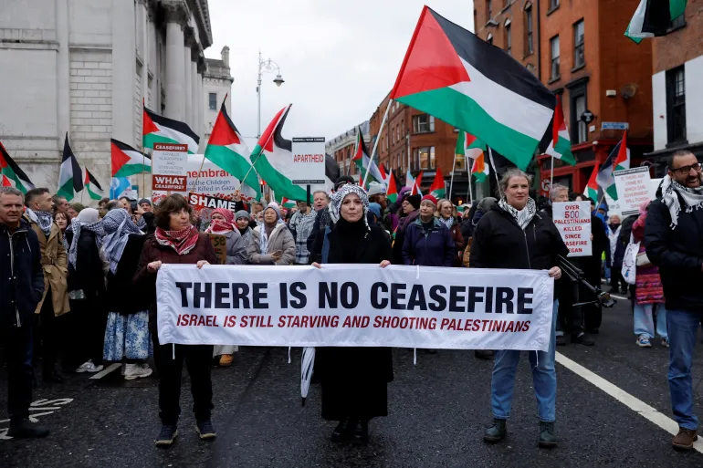 Demonstrators hold a banner and flags in support of Palestinians during a protest in relation to the ceasefire in Gaza, in Dublin, Ireland